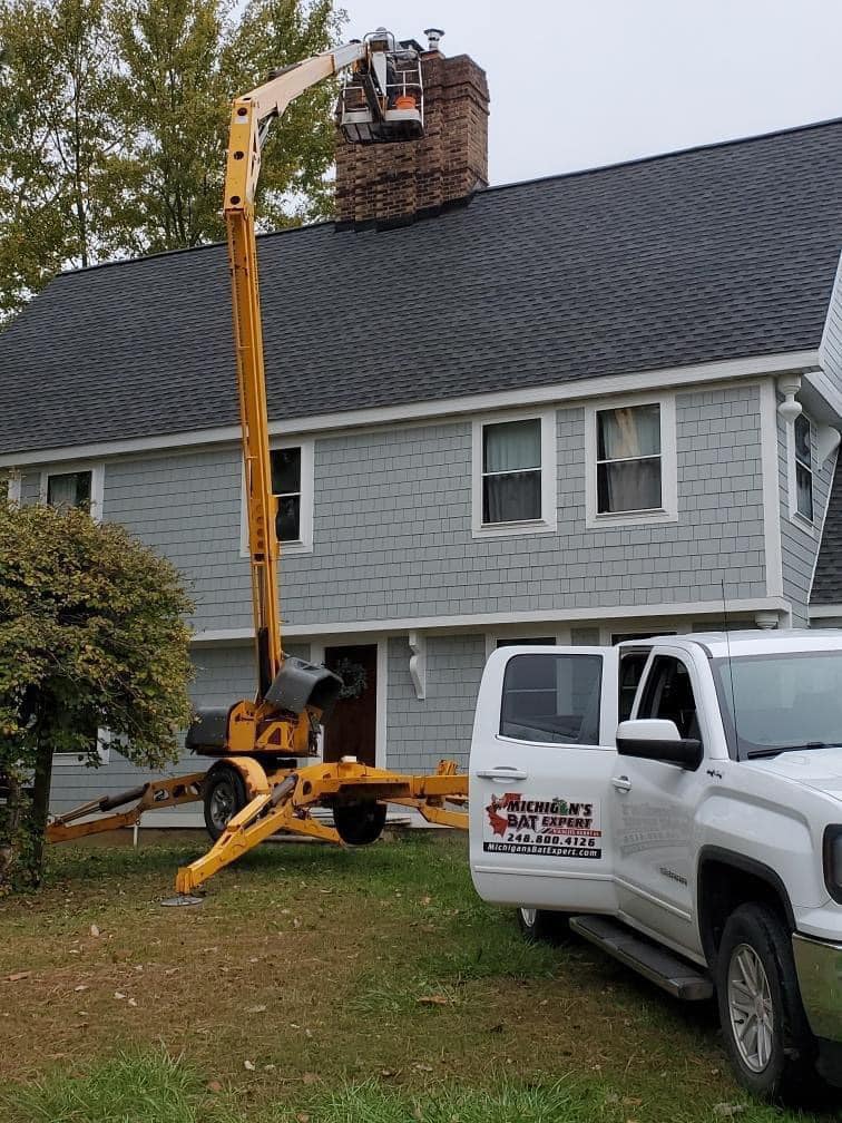 Bat removal team in Michigan using a lift to inspect the roof and chimney.